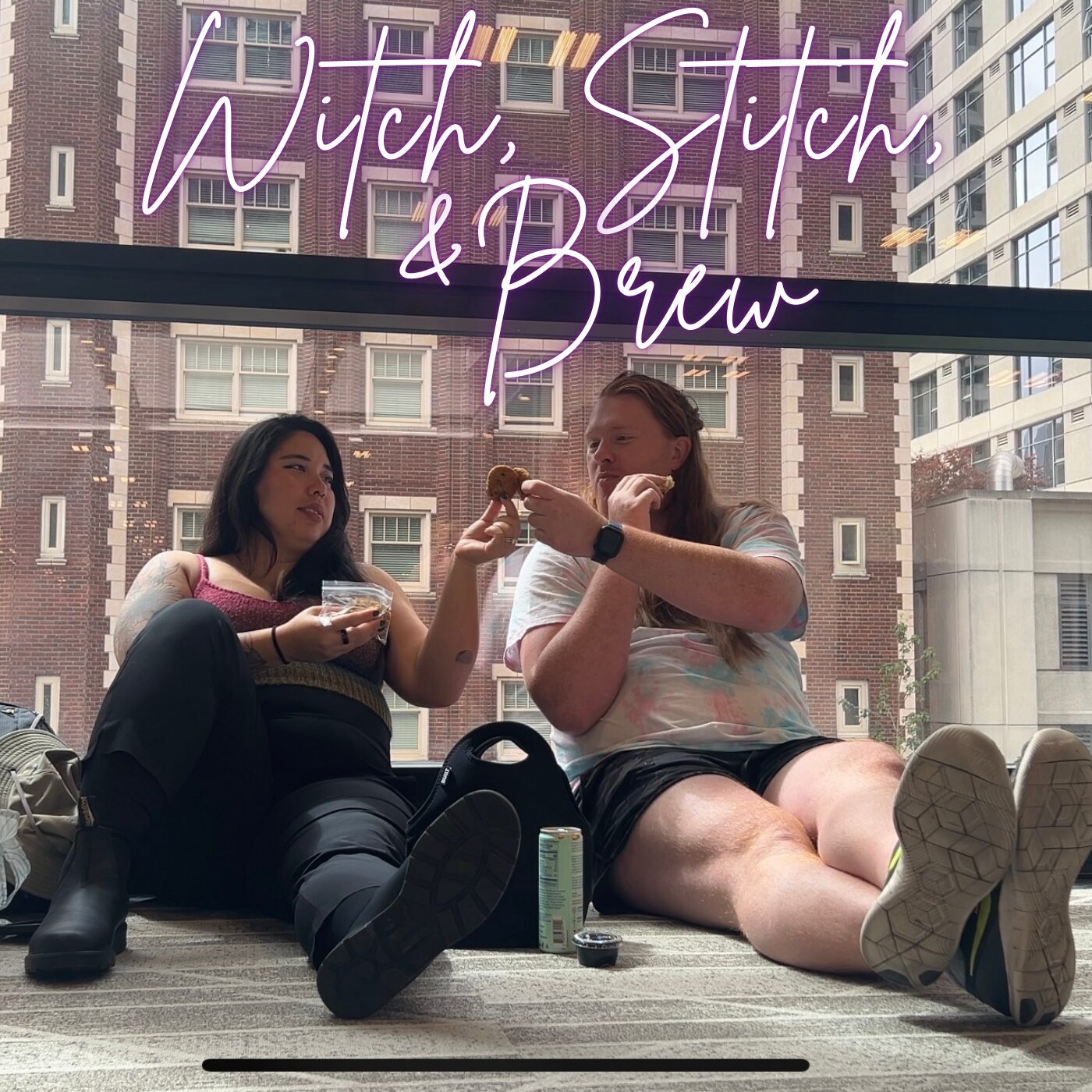 2 women sitting on the floor up against a large window with a brick building behind them, are toasting with cookies. In script font above their heads are the words Witch, Stitch, & Brew