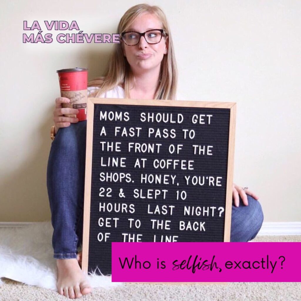 A smirking blond woman in glasses sits barefoot against a wall holding a red to-go cup in one hand while balancing a large black board against her legs. The board reads: moms should get a fast pass to the front of the line at coffee shops. Honey, you're 22 & slept 10 hours last night? Get to the back of the line.
In a bright pink box the words read: Who is selfish, exactly?