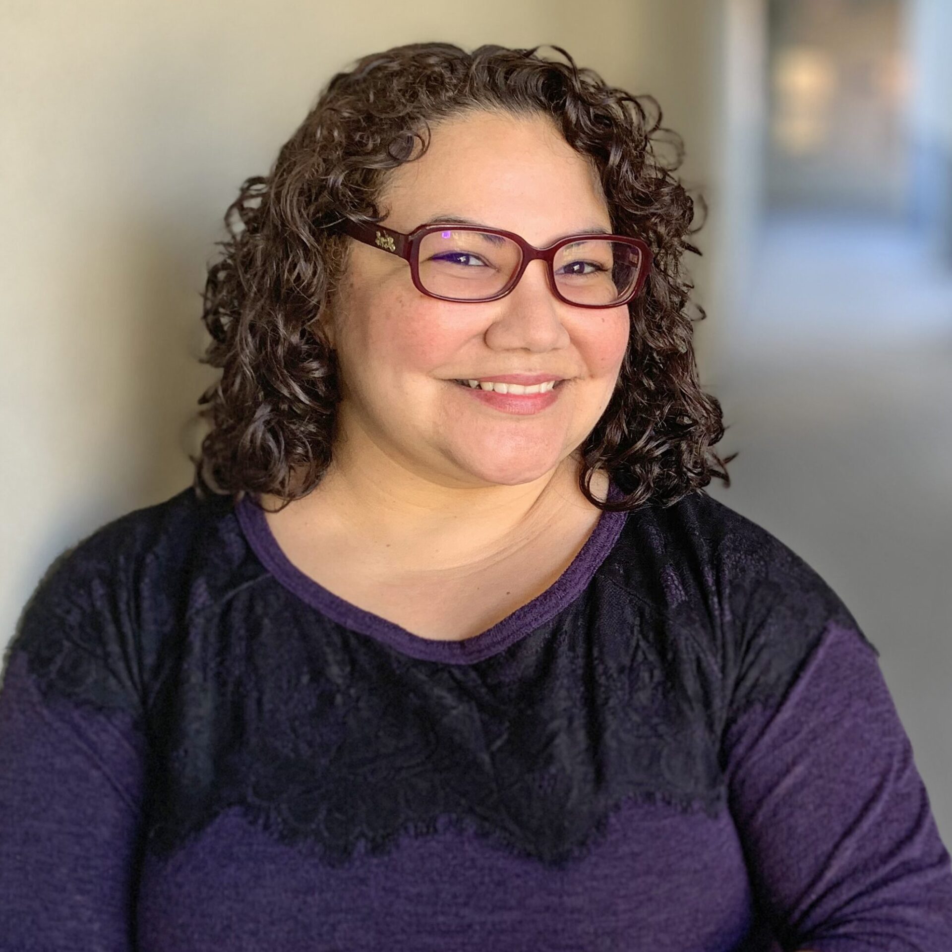 Paulette Erato in a purple shirt and red glasses