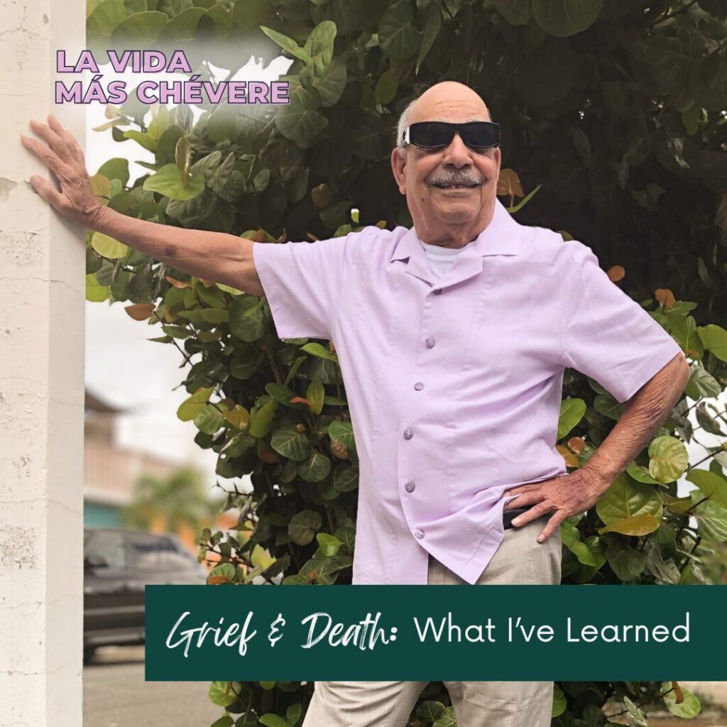 Bald man in sunglasses, khakis, and a lavender shirt stands with one arm on a light post, the other on his hip, on a residential street in San Juan, Puerto Rico