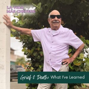 Bald man in sunglasses, khakis, and a lavender shirt stands with one arm on a light post, the other on his hip, on a residential street in San Juan, Puerto Rico